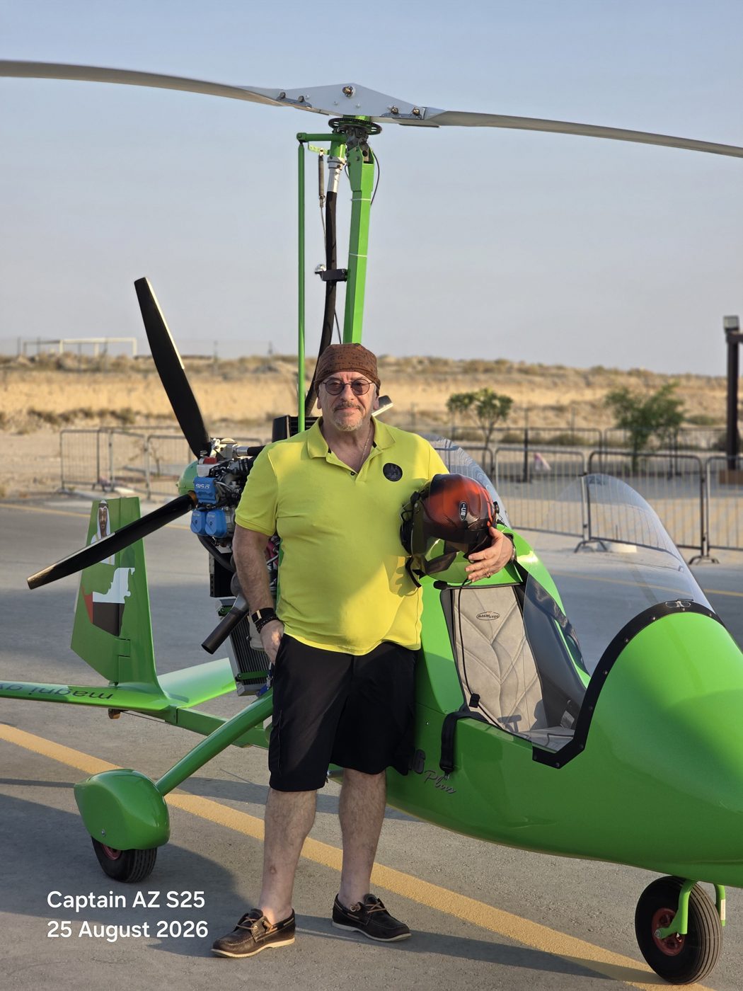Bashar Dahabra standing beside a green Magni gyroplane, holding his flying helmet